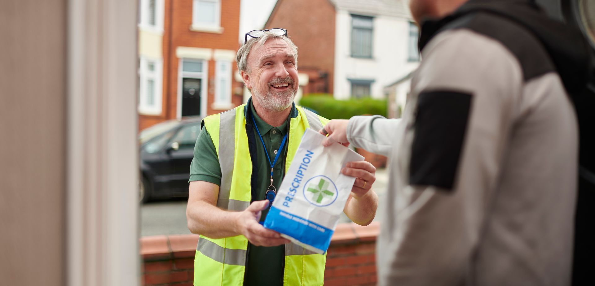 Friendly courier handing prescription bag to customer at door offering pharmacy delivery service.