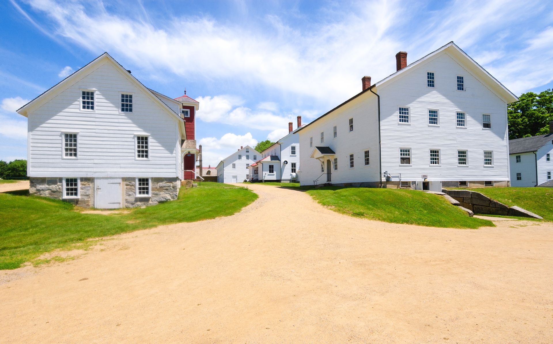 a row of white houses on a dirt road