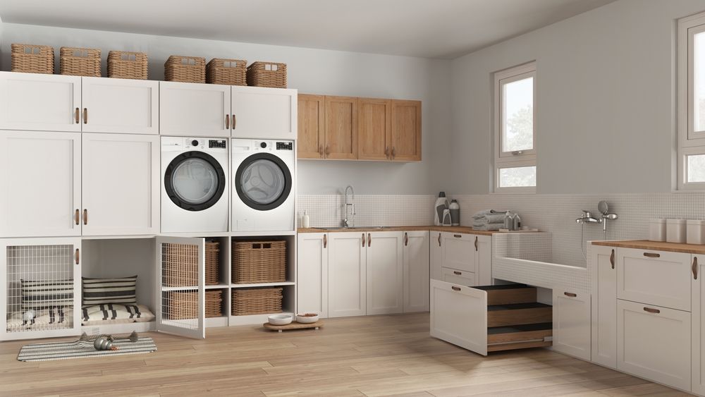 Laundry room with white cabinets, washer and dryer, baskets, and sink.