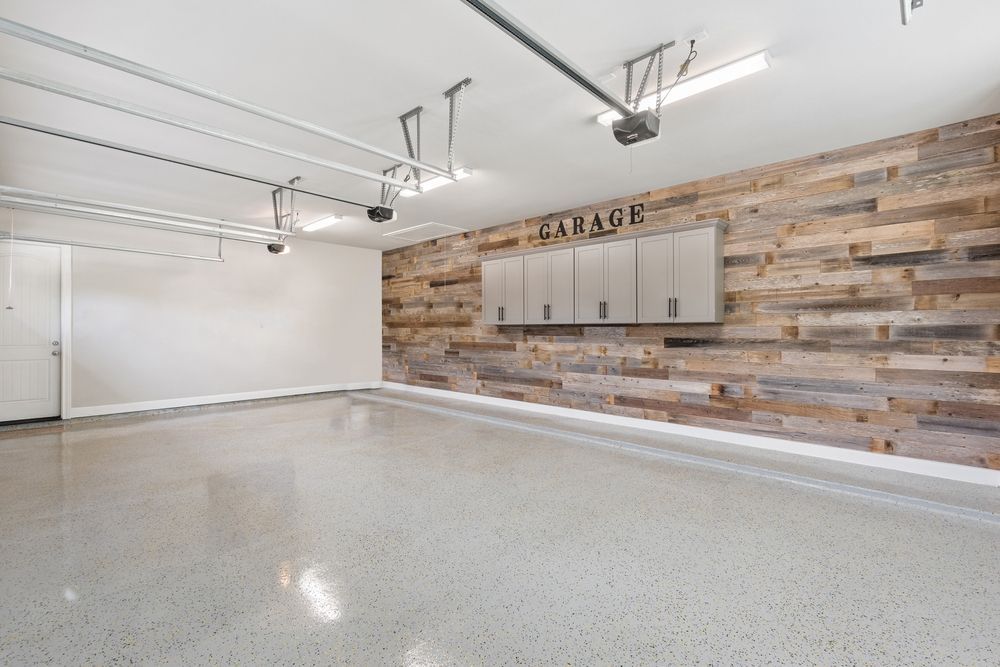 Empty garage with polished concrete floor, wood accent wall, and cabinets.