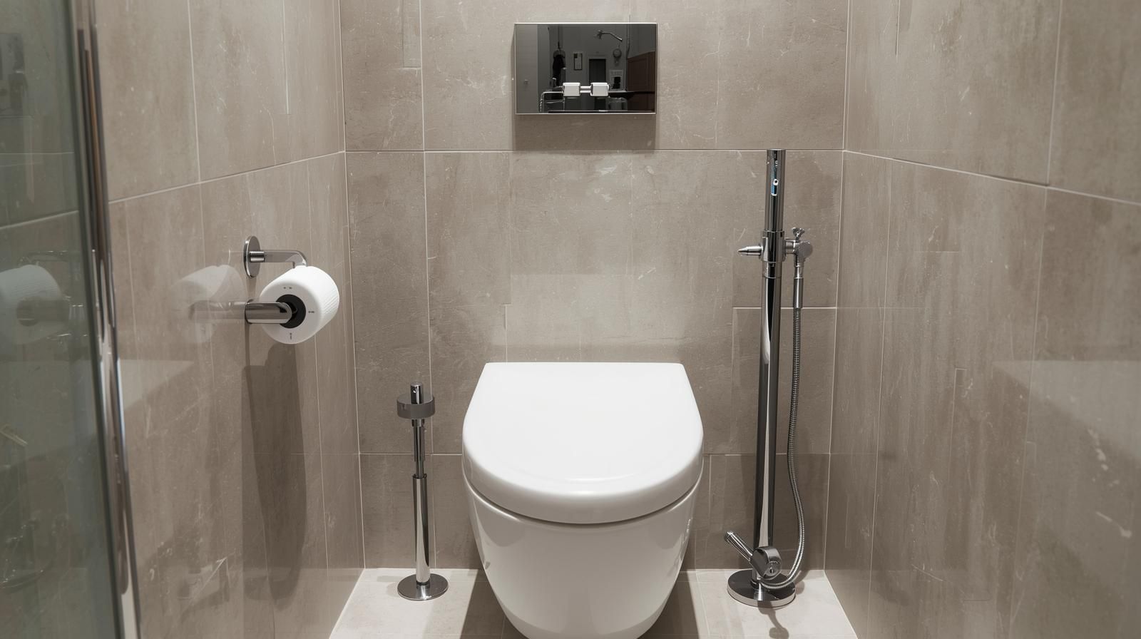 Toilet with bidet and toilet paper holder on a tiled wall. Chrome fixtures, neutral tones.