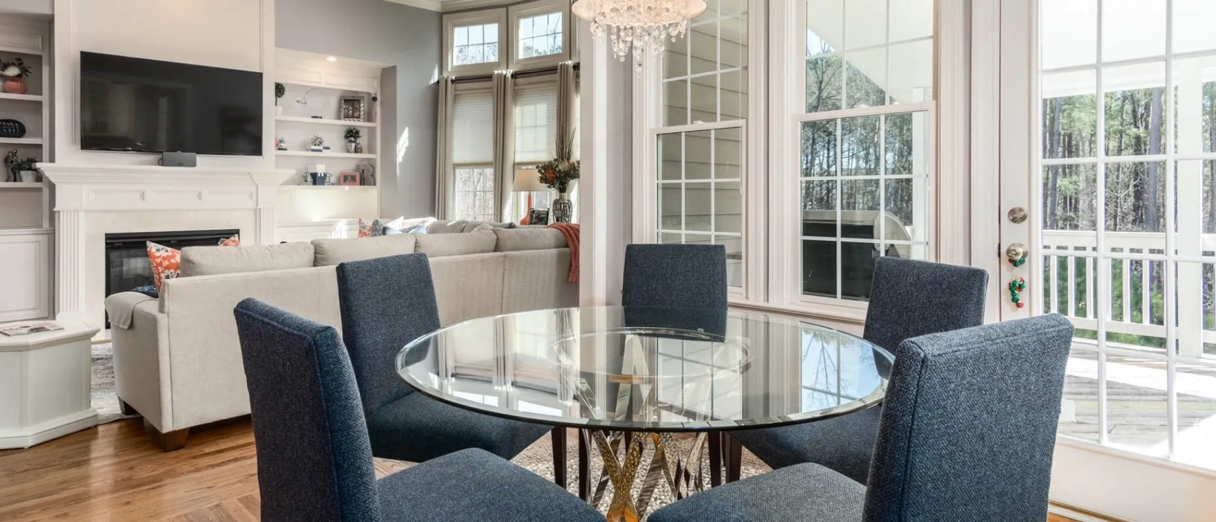 A dining room with a round glass table and blue chairs.