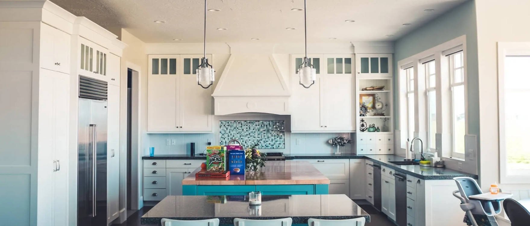 A kitchen with white cabinets and a blue island in the middle.