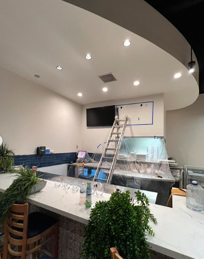 A restaurant is being remodeled and a ladder is hanging from the ceiling.