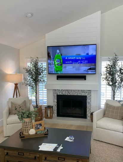 A living room with a fireplace and a flat screen tv on the wall.