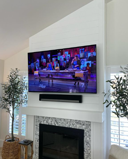 A flat screen tv is hanging over a fireplace in a living room.