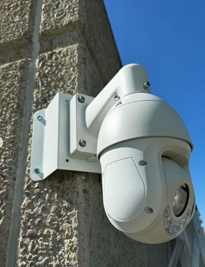 A white security camera mounted to a brick wall
