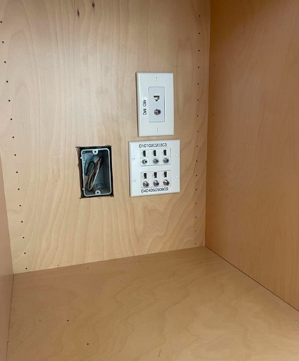 A wooden cabinet with a few electrical outlets on it