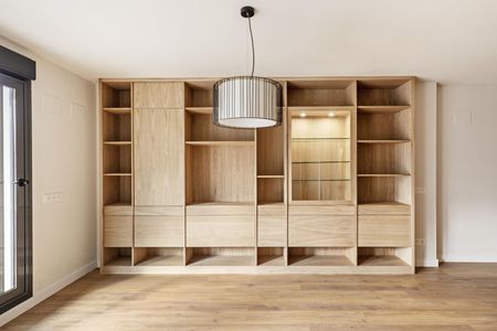 A living room with a lot of wooden shelves and drawers.