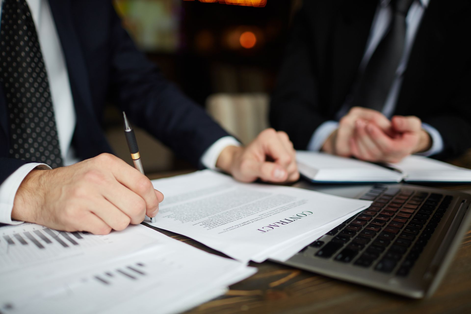 Two men are sitting at a table signing a contract.