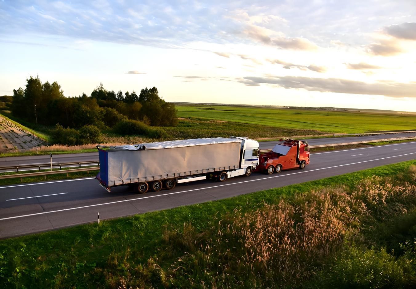 A Semi Truck is Driving Down a Highway Next to a Field — Airlie Towing & Tilt Tray Hire In Cannonvale, QLD