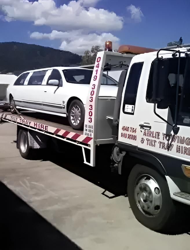 A Tow Truck With a Limousine on the Back of It — Airlie Towing & Tilt Tray Hire In Cannonvale, QLD