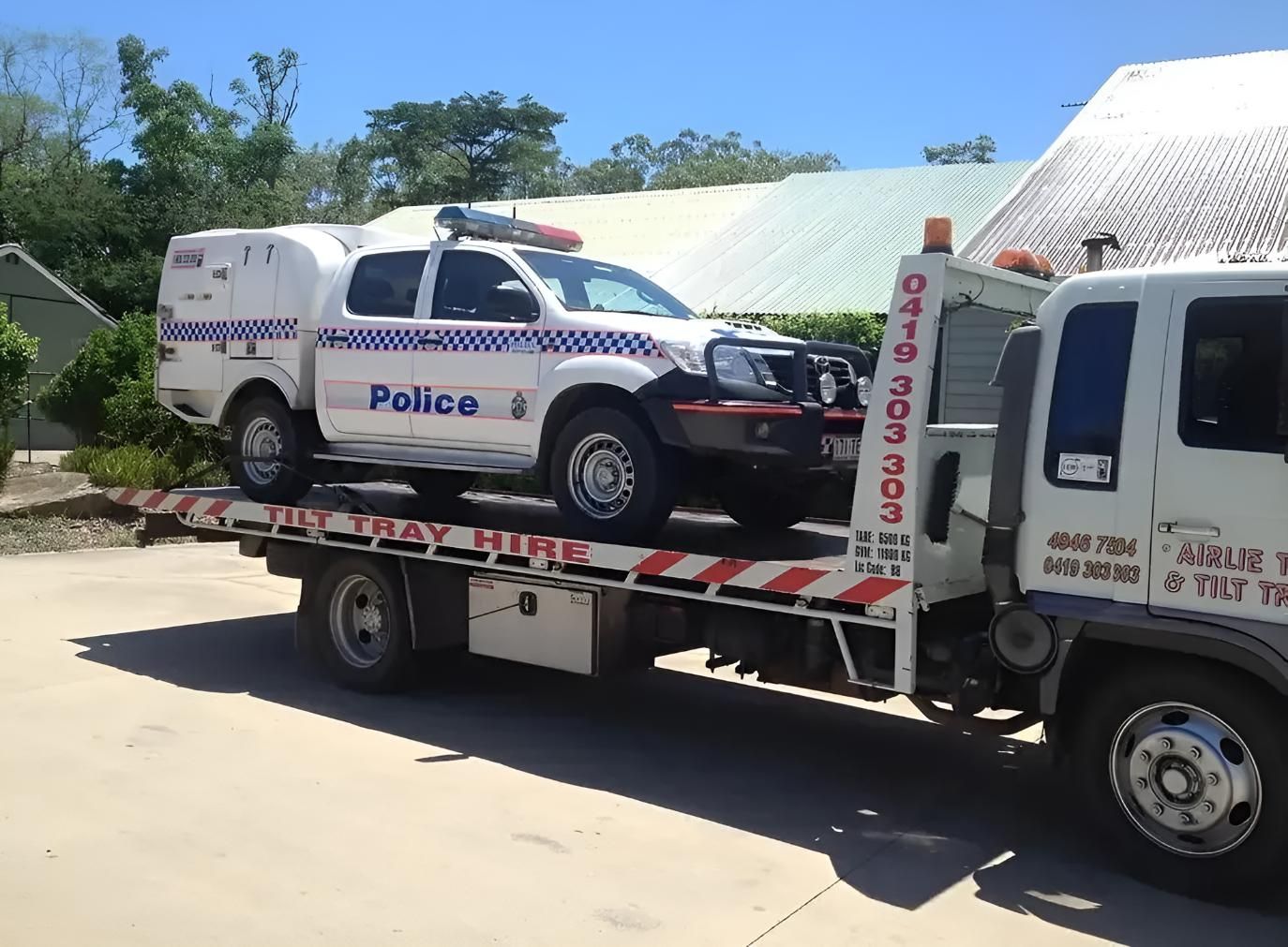 A Police Truck is Being Towed by a Tow Truck — Airlie Towing & Tilt Tray Hire In Cannonvale, QLD