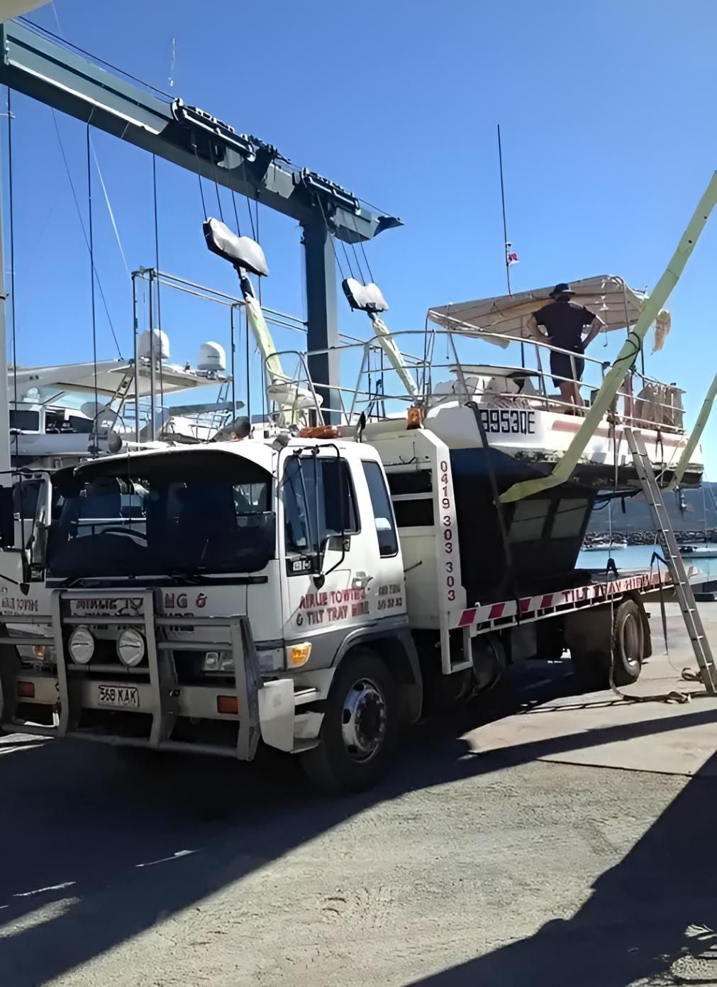 A Tow Truck is Carrying a Boat on a Trailer — Airlie Towing & Tilt Tray Hire In Cannonvale, QLD