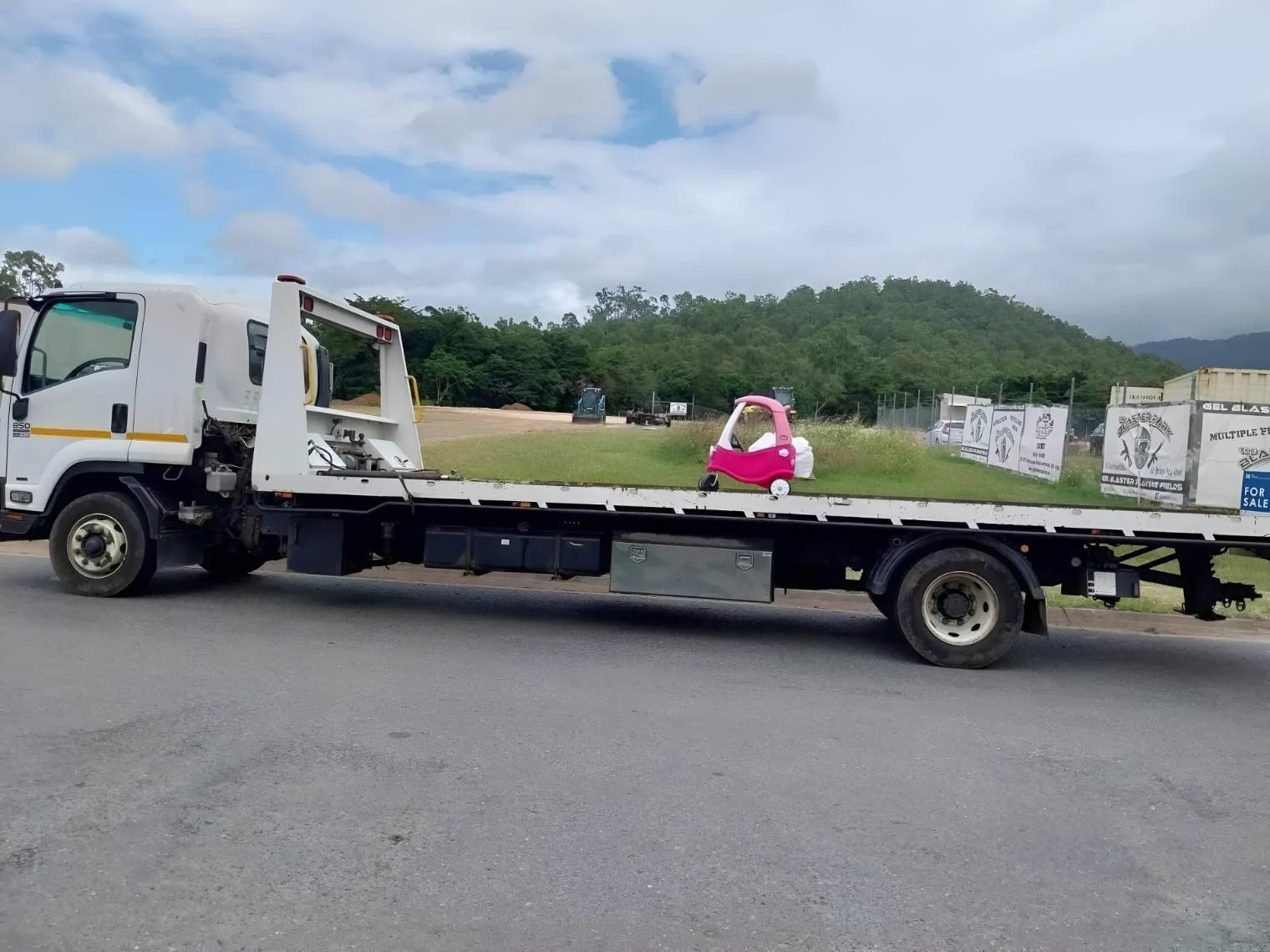 A Tow Truck With a Red Car on the Back is Parked on the Side of the Road — Airlie Towing & Tilt Tray Hire In Cannonvale, QLD