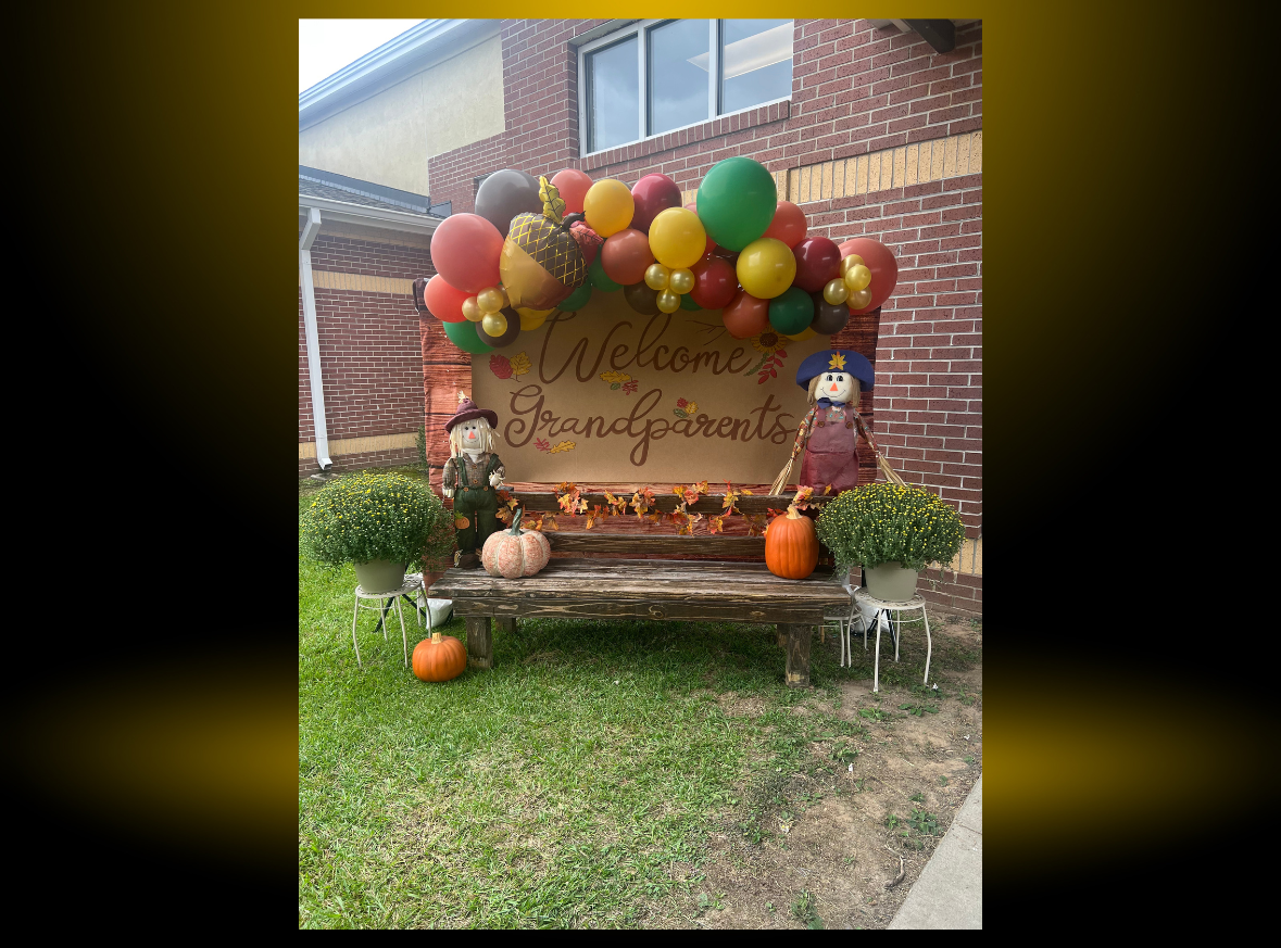 a sign with balloons and pumpkins on it is in front of a brick building .