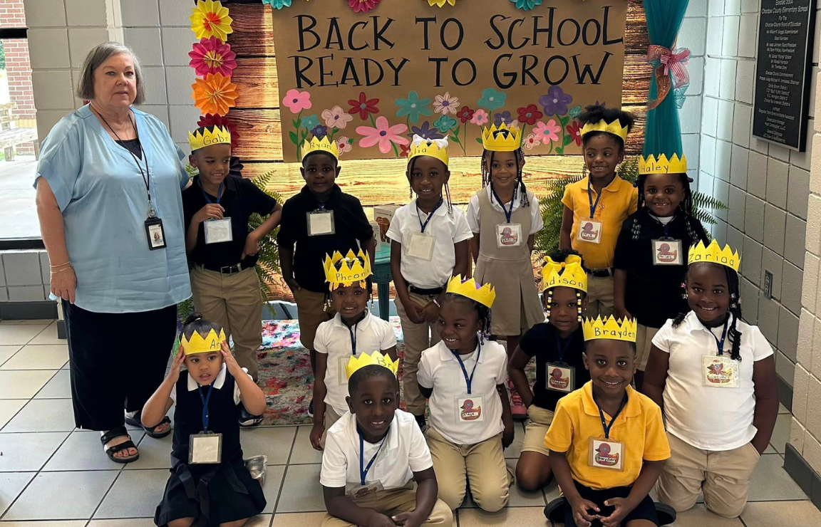 a group of children wearing crowns are sitting in front of a sign that says `` back to school ready to grow '' .