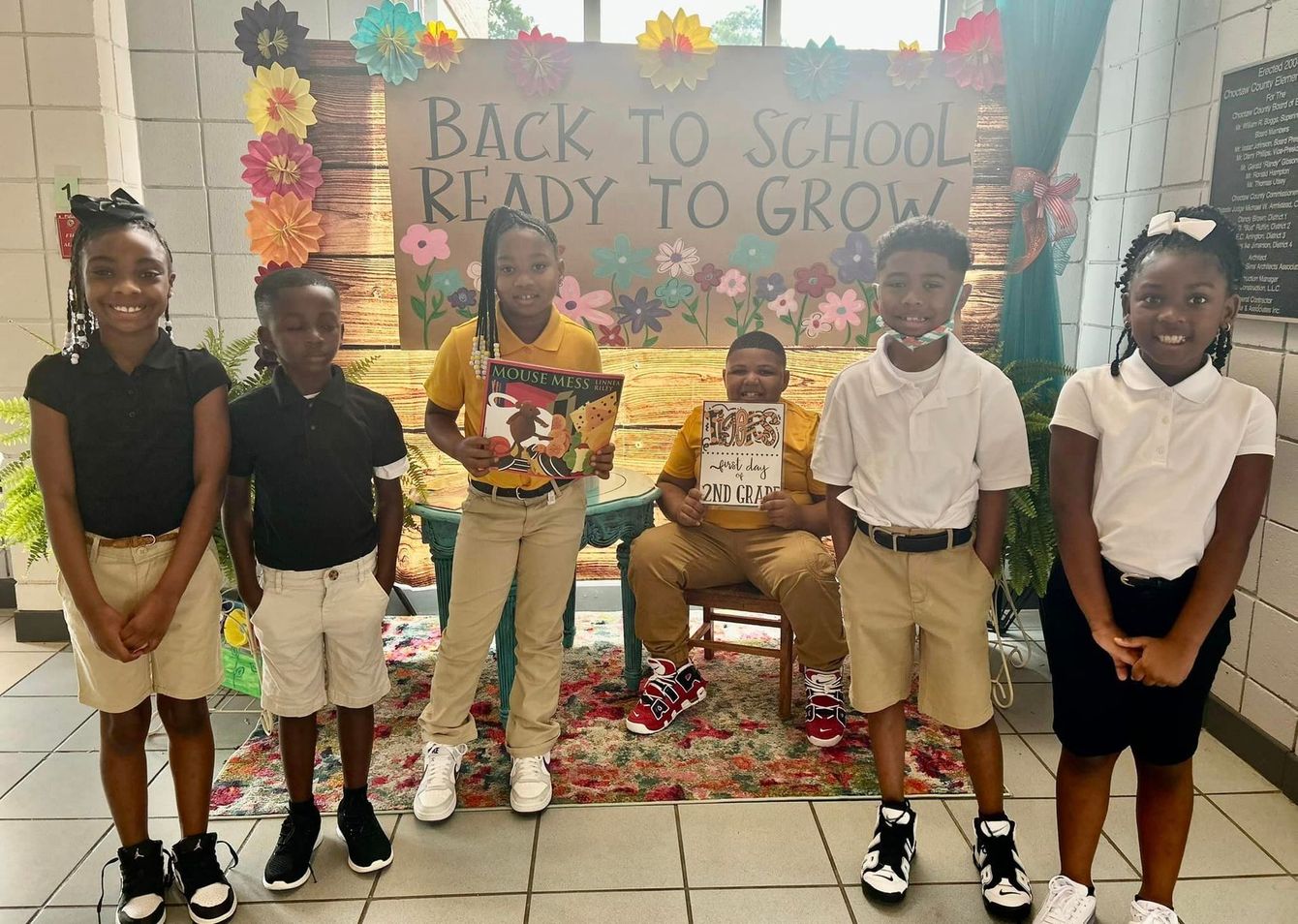 a group of children are standing in front of a sign that says back to school ready to grow .