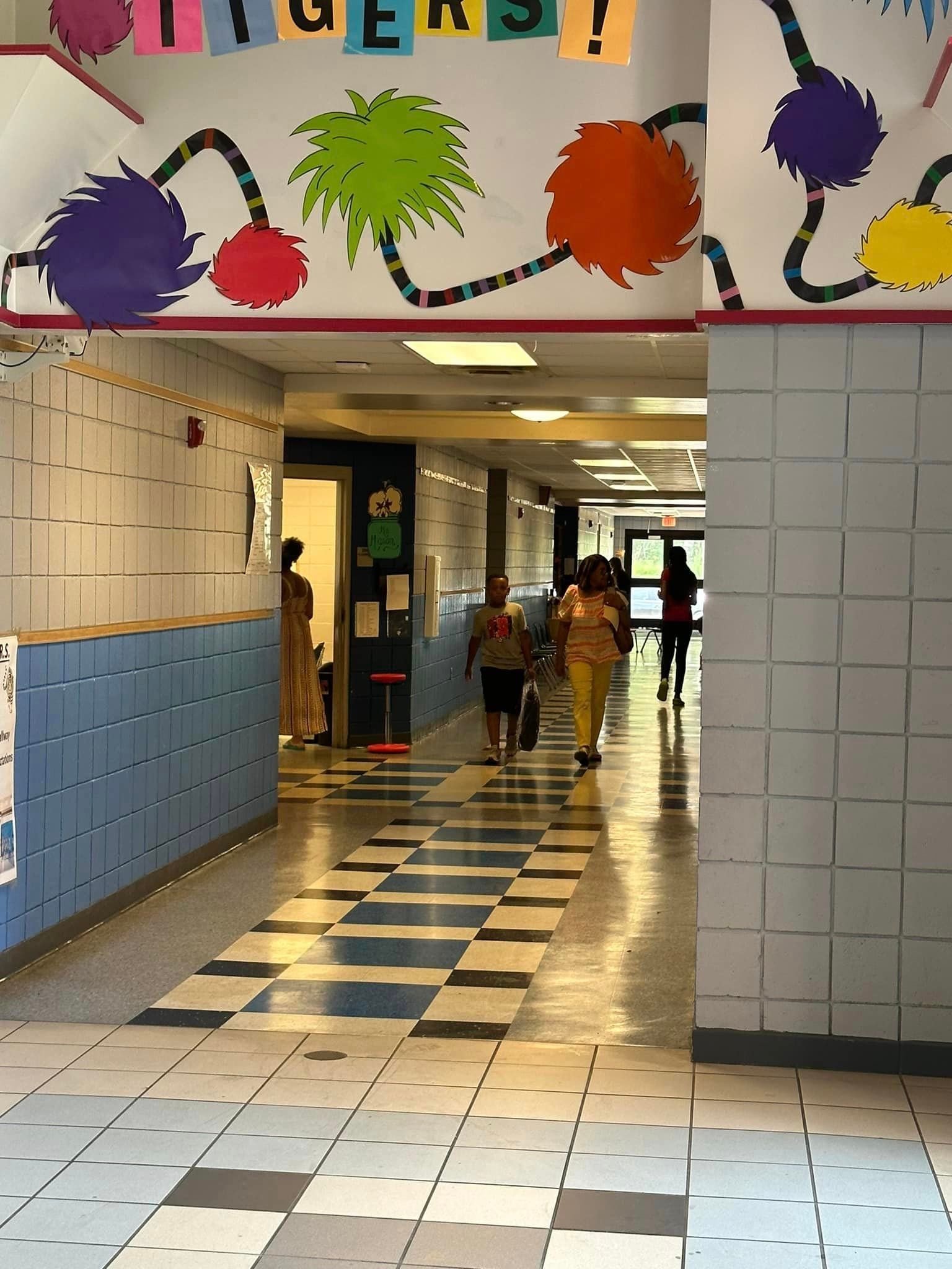 a group of people are walking down a hallway in a school .