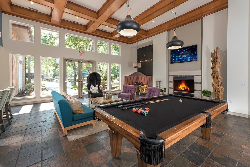 Communal lounge with pool table, fireplace, TV, and lounge seating by large windows.
