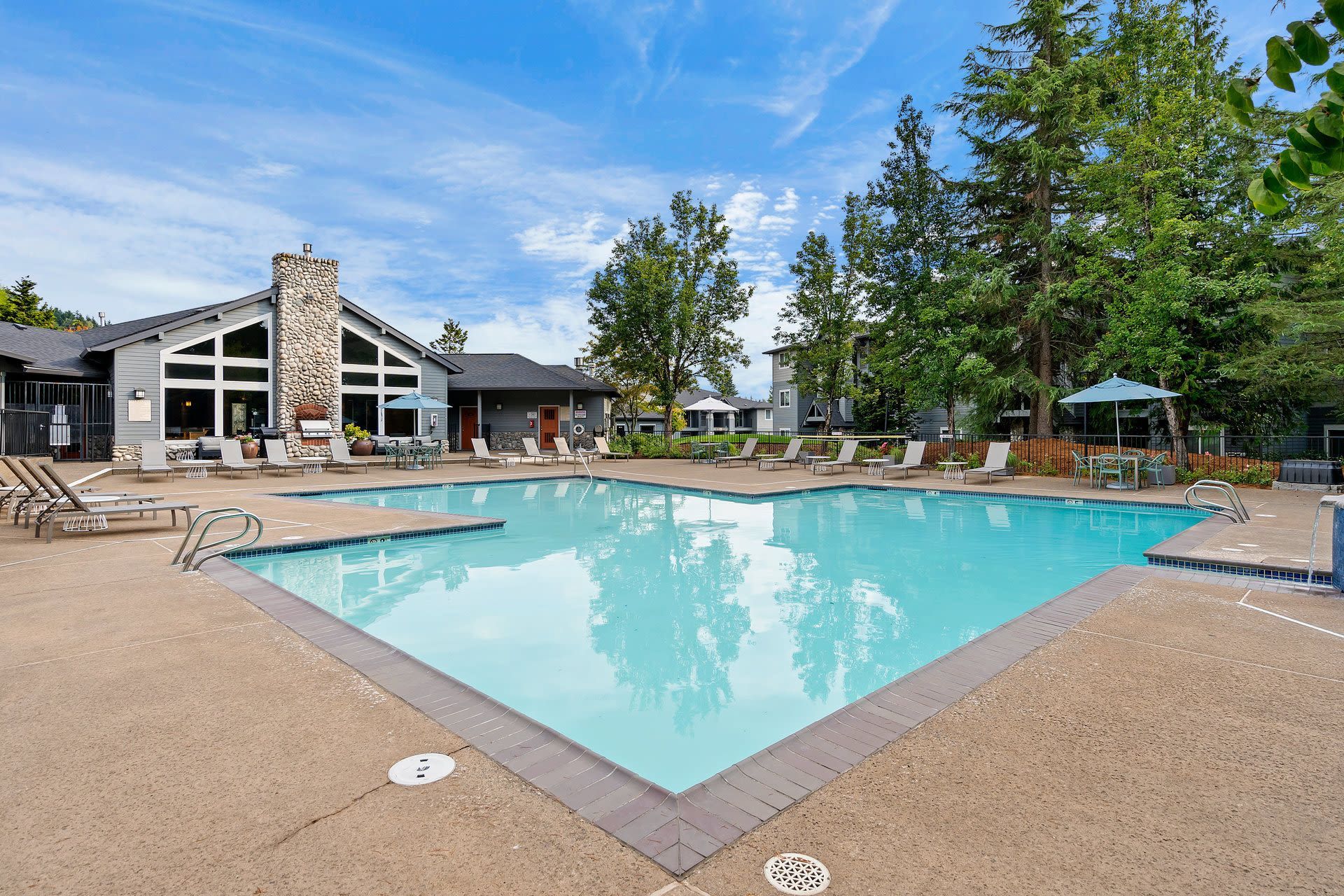 Outdoor pool area at a residential community with lounge chairs and umbrellas.