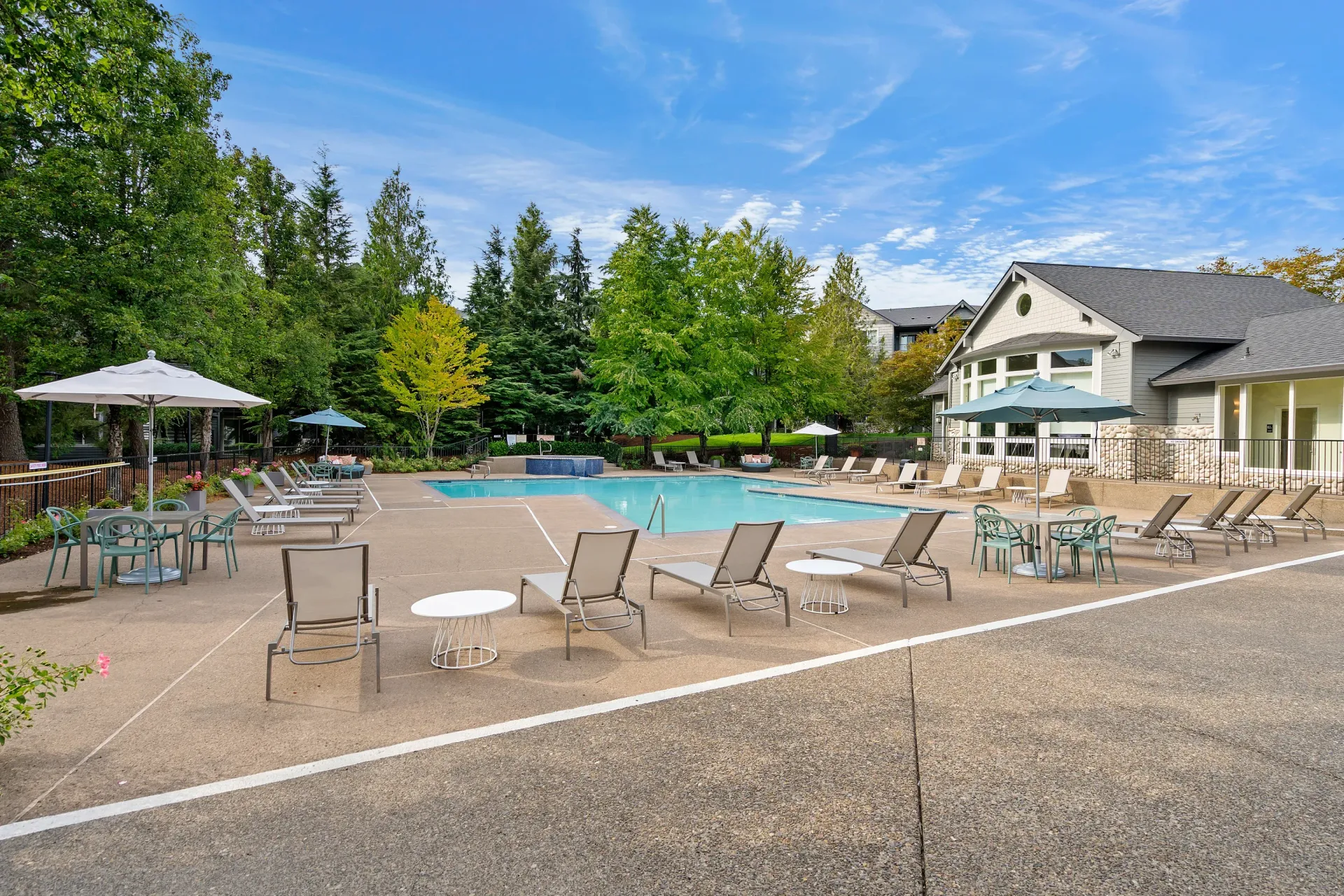 Outdoor pool area at a multifamily community with lounge chairs and umbrellas.