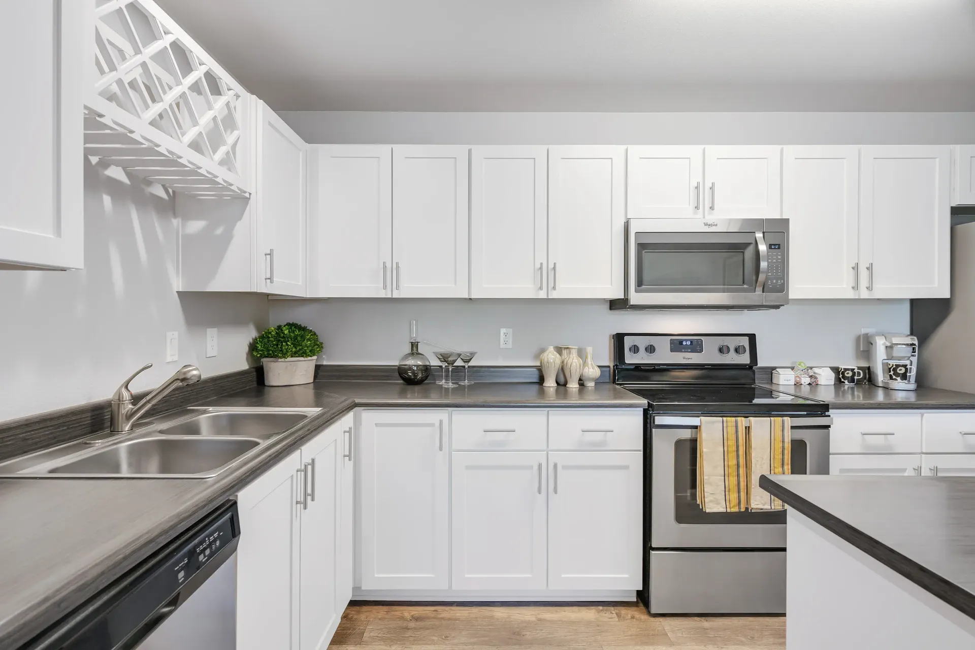 Modern white kitchen with stainless steel appliances, double sink, and gray countertops.