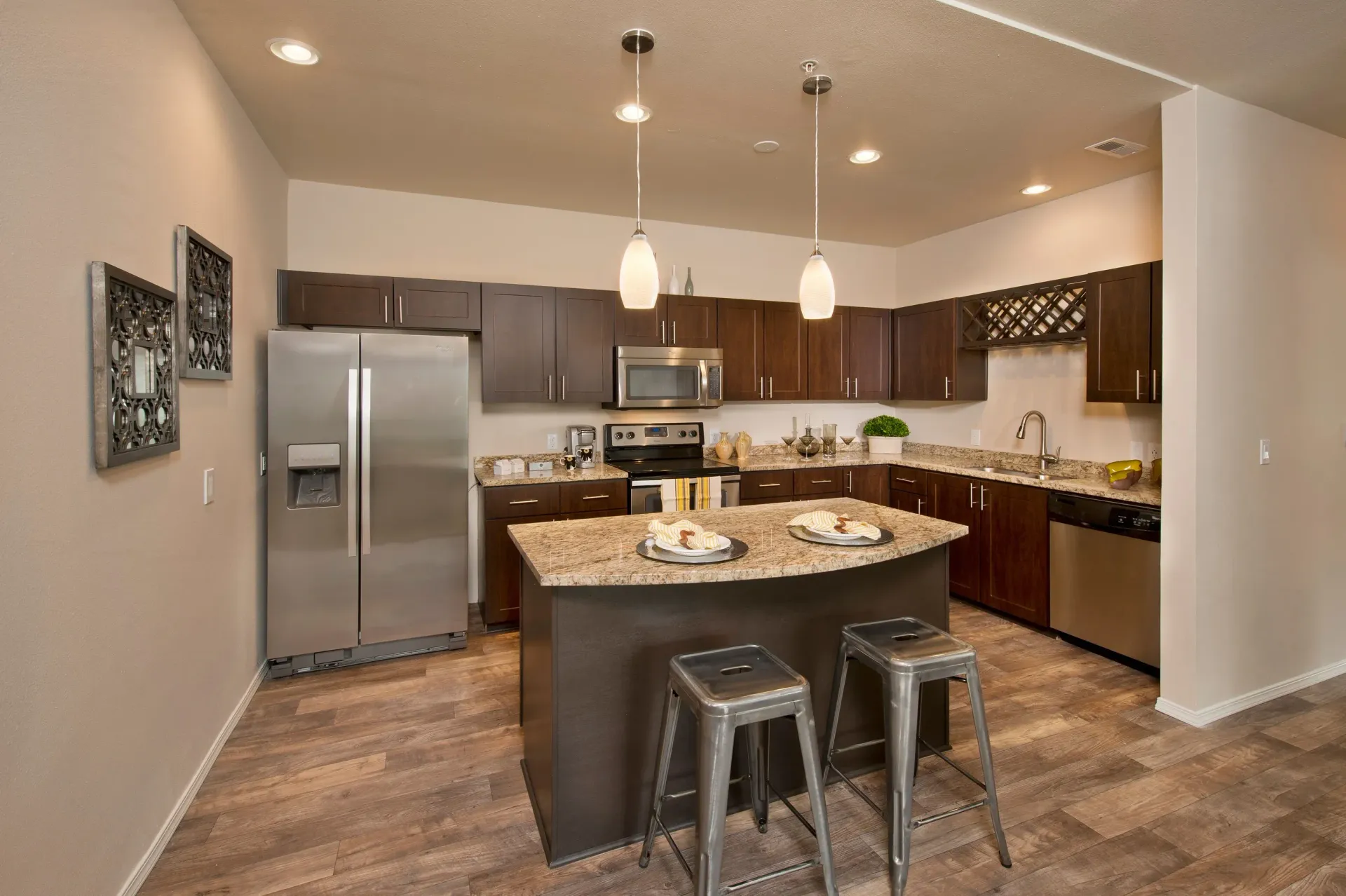 Modern kitchen with granite countertops, dark wood cabinets, stainless steel appliances, and a central island.