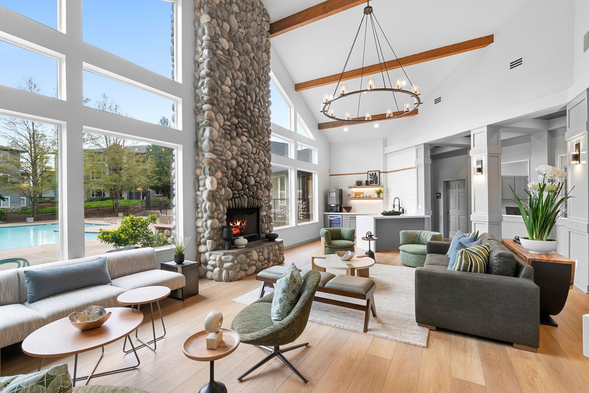 A modern, open-concept club room with a large stone fireplace, floor-to-ceiling windows, and contemporary furniture.