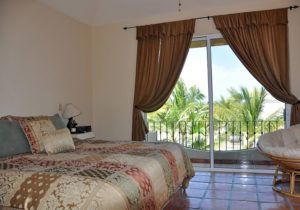 A bedroom with a bed , chair and sliding glass doors.