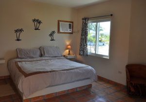 A bedroom with a bed , chair , window and air conditioner.