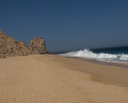 A sandy beach with waves crashing on the shore