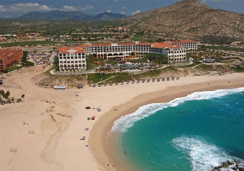 An aerial view of a beach with a large building in the background