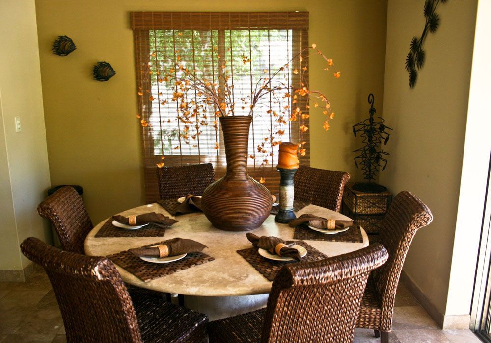 A dining room table with wicker chairs and plates on it
