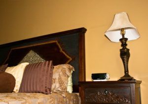 A lamp is sitting on a nightstand next to a bed.