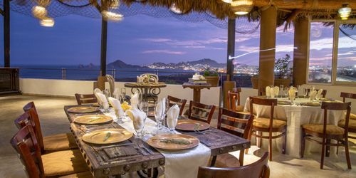 A restaurant with tables and chairs and a view of the ocean.