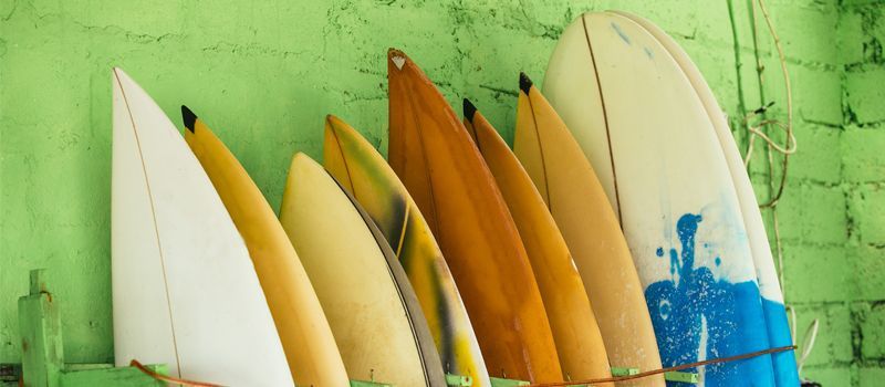 A row of surfboards are hanging on a green wall.