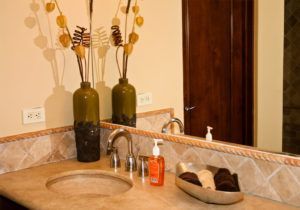 A bathroom with a sink , mirror and vases on the counter.