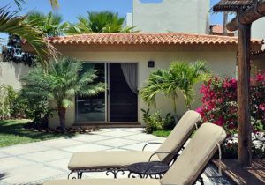 Two lounge chairs are sitting in front of a house with a sliding glass door.
