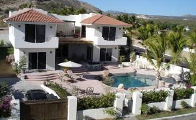 A large white house with a pool in front of it