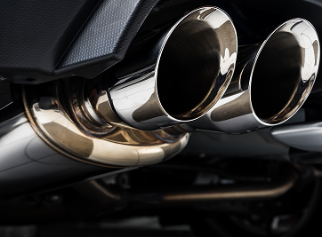 Shiny dual exhaust pipes on a dark car. | Zee's Alignment & Autocare