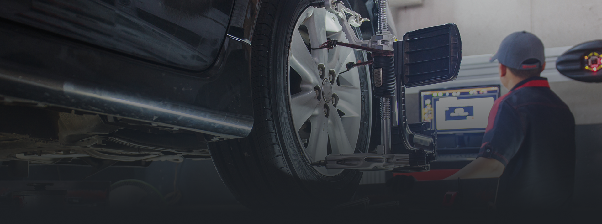Car wheel being aligned by a mechanic using a computer. | Zee's Alignment & Autocare