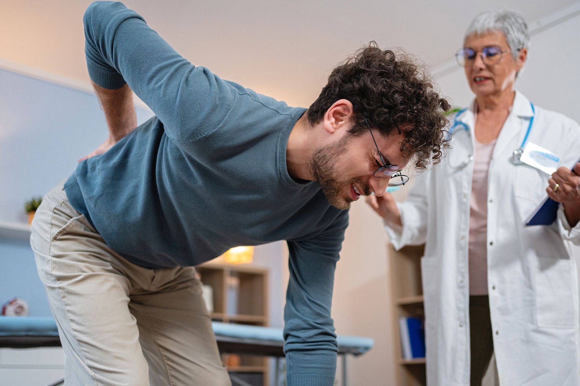 A man with back pain is being checked by a doctor. A man with back pain is being checked by a doctor.