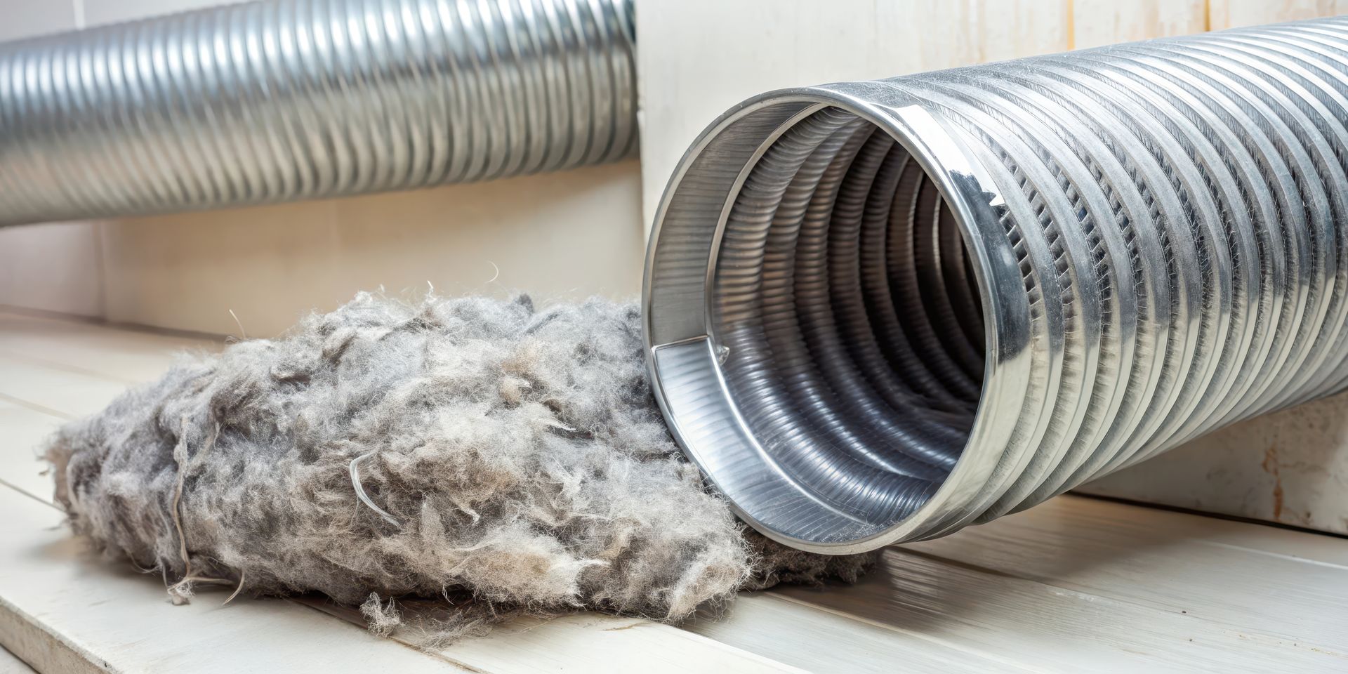 A close up of a metal duct with a pile of dust coming out of it.