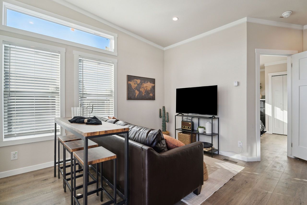 Living room with a bar, leather couch, TV, and world map on wall.