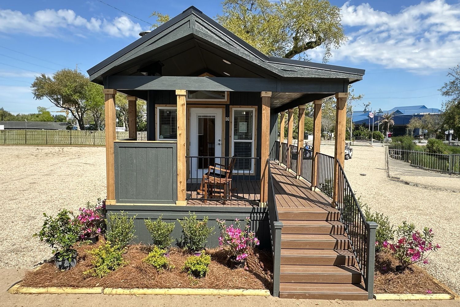 Tiny gray house with porch, wheelchair ramp, and landscaping.