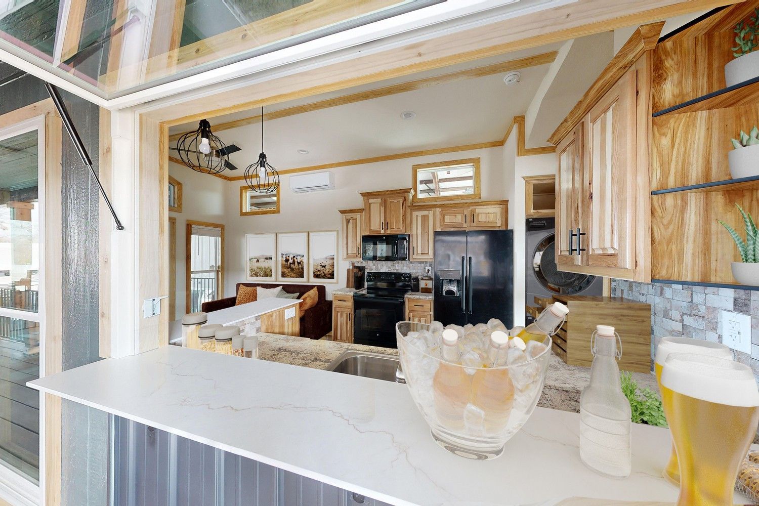 Kitchen interior with a bar and a view of the cooking area: cabinets, appliances, and a pass-through window.