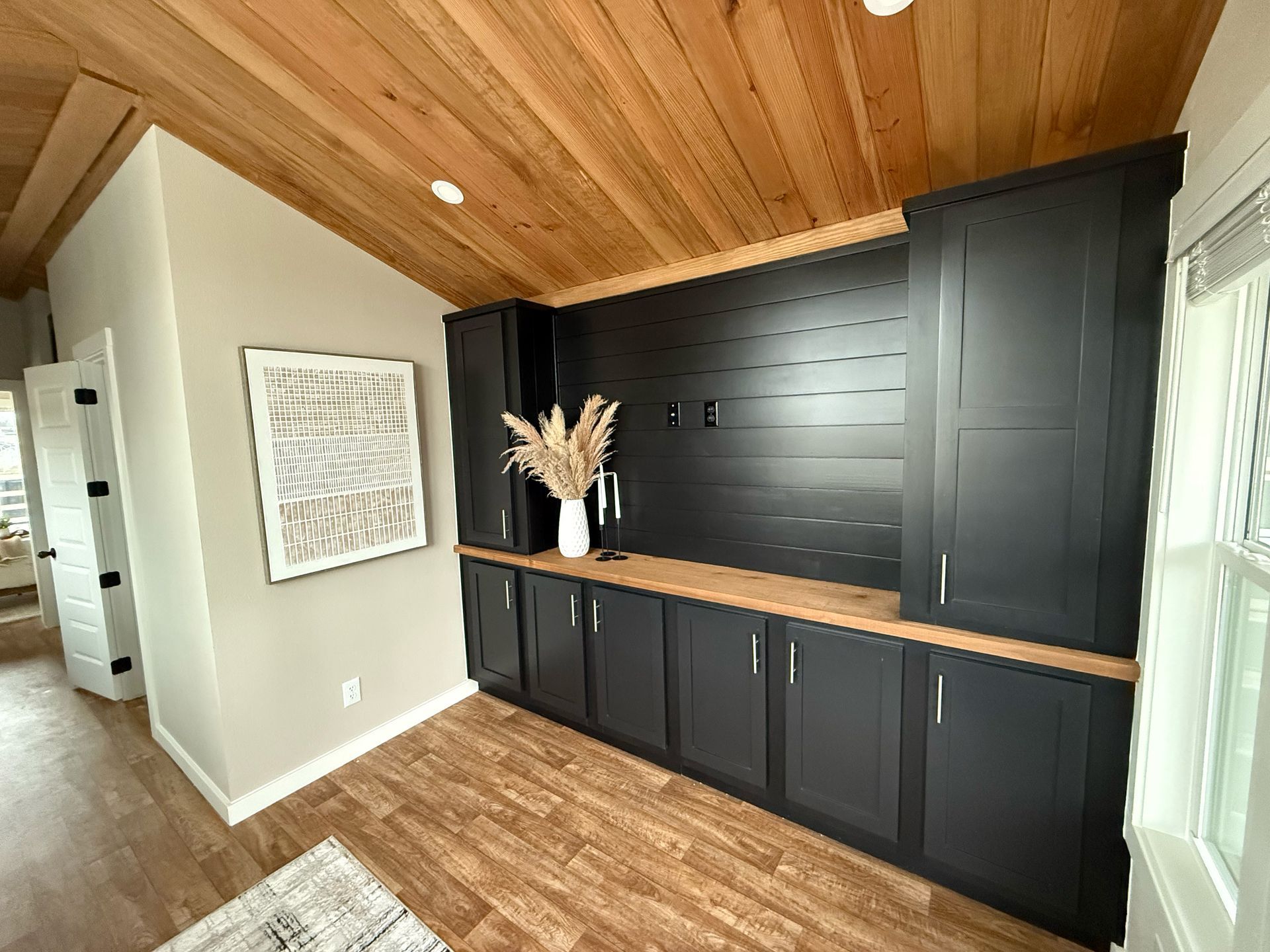 Interior room with black cabinetry, wood ceiling, and tan walls.
