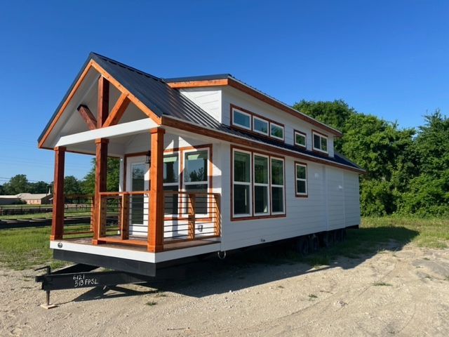 side angle of a white tiny home with red wood railing and accents