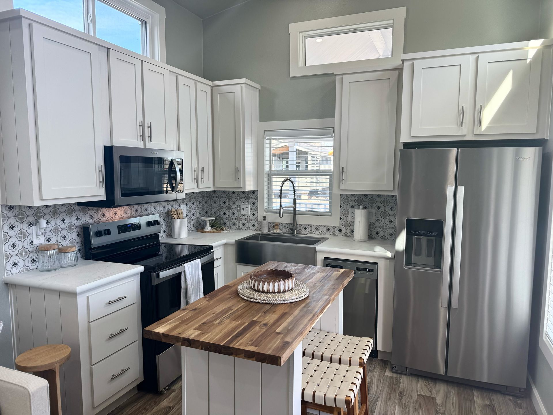 Small kitchen with white cabinets, stainless steel appliances, and a wooden island.